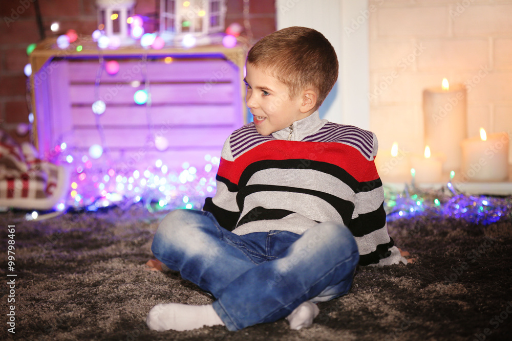 Little boy sitting at home on a Christmas background