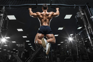 Wall Mural - Athlete muscular fitness bodybuilder male model pulling up on horizontal bar