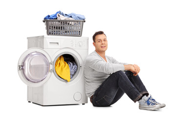 Wall Mural - Young man sitting by a washing machine