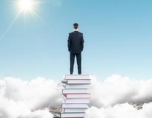 Poster - Businessman staying on the stack of books among clouds at blue s