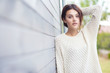Beautiful natural young brunette woman wearing knitted sweater by the house. Fashion concept.