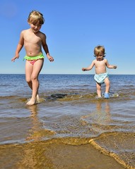little funny cute girls running on coast together. on the beach in summer
