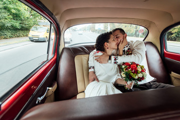 Wall Mural - stylish bride and happy groom inside of retro car having fun and