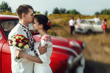 Wall Mural - stylish bride and happy groom near car on the background of natu