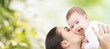 © Syda Productions - happy mother kissing baby over green background