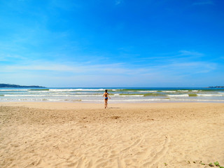 Wall Mural - Young woman run into the ocean in Weligama bay