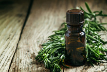 Rosemary Essential Oil In A Small Bottle And Fresh Rosemary On A