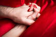 © bluebeat76 - Young couple holding hands sensually on red silk bed.