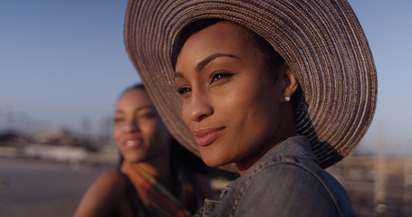 Black women best friends looking out over ocean while standing o