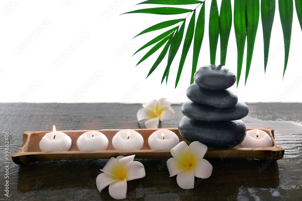 Spa stones with candles, plumeria and bamboo, isolated on white