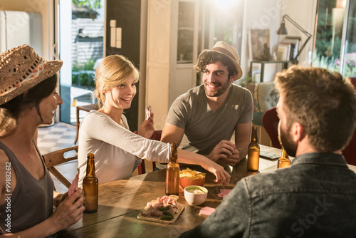 Fotografie, Obraz Friends having a drink and playing cards on a sunny evening. The