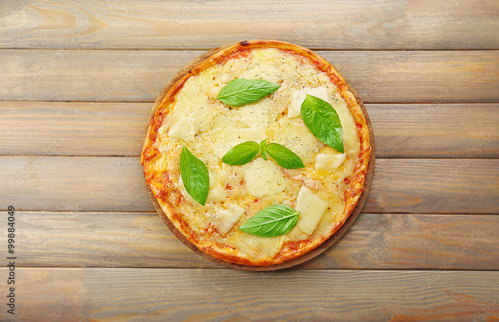 Tasty pizza decorated with basil  on wooden background, close up