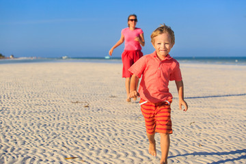 happy little boy with mother running on beach