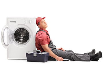 Poster - Exhausted plumber sitting by a washing machine