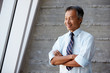 © Monkey Business - Asian Businessman Standing Against Wall In Modern Office