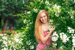 © ottochka - Woman stands near a garden of white roses