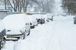 Cars in a row under the snow blizzard