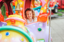 Happy Child Girl Riding Train On Funfair On Summer Vacation