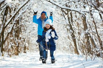 father and daughter playing in the snow in winter