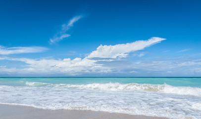 Beautiful blue sky holiday.  Varadero beach scene - getaway on a vacation beach in Cuba. Warm ocean waves gently lap against a Cuban beach. 