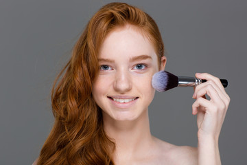 Sticker - Cheerful woman with red hair doing make up on cheeks