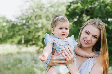 Young mother playing with her little daughter on the nature, motherhood, tenderness, childhood, tenderness, lifestyle