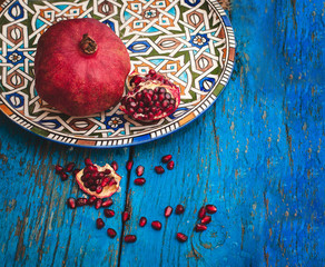 red ripe pomegranate in dish oriental style with copy space on w