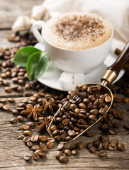 Close-up of coffee cup with roasted coffee beans on wooden backg