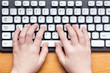 © Alexander Mak - Top view of hands typing on computer keyboard
