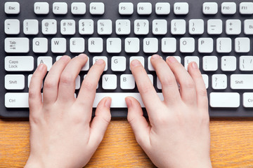 top view of hands typing on computer keyboard