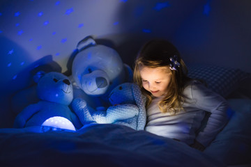 Wall Mural - Little girl reading a book in bed