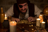 Pirat mit Goldschatz hinter vielen Kerzen