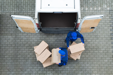 Delivery Men Unloading Cardboard Boxes From Truck On Street