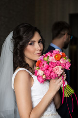 Beautiful brunette bride in wedding dress smiling and posing ind