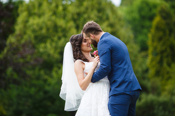 Happy newlywed couple smiling and hugging in park field surround