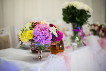 Wall Mural - Beautiful freshly cut flowers in a glass vase on wedding recepti
