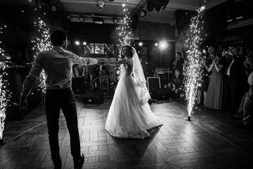 beautiful newlywed couple first dance at wedding reception surrounded by smoke and lights and sparks