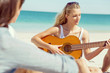 © Sergey Nivens - Beautiful young woman playing guitar on beach