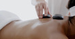 © Dash - African-american woman receiving a massage with hot stone in a spa center