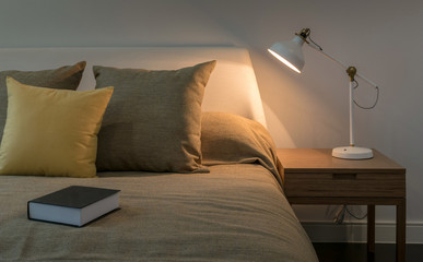 cozy bedroom interior with book and reading lamp on bedside table