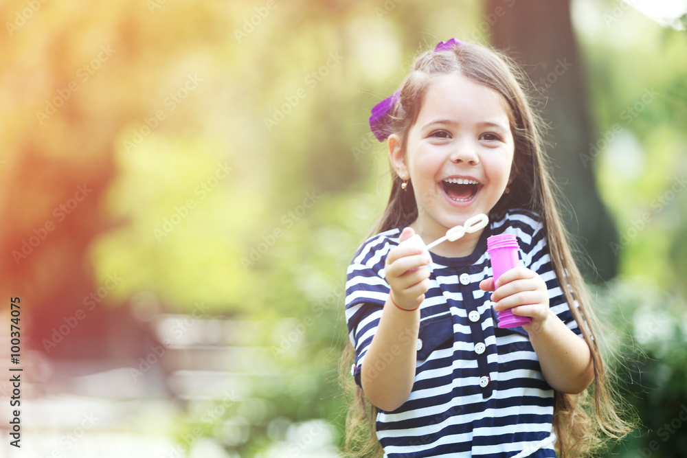Happy little girl with bubbles in the park