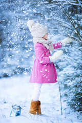 Wall Mural - Adorable little girl having fun in the snow on Christmas at winter forest outdoors