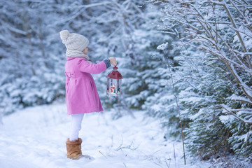 Wall Mural - Adorable little girl with flashlight on Christmas at winter forest outdoors