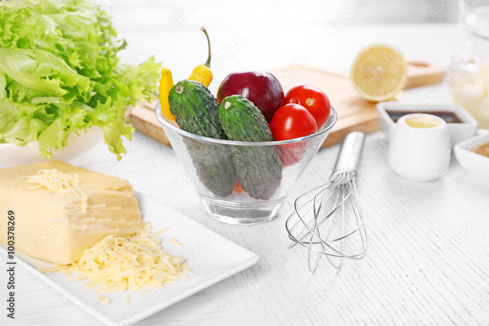 Kitchen utensils and ingredients for salad on table, on light background