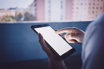 Wall Mural - Girl touching screen of her phablet on the blurred city background. 