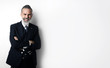 © SFIO CRACHO - Portrait of bearded businessman wearing trendy suit, stands against the empty white wall and smiling. Wide.