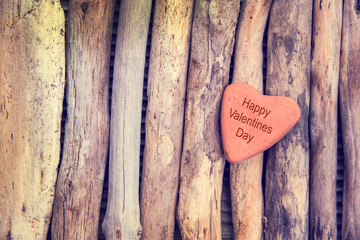 Wall Mural - happy valentines day, stone in the shape of a heart on wood background