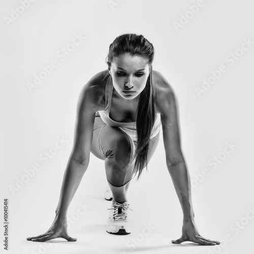 dopasowanie-lekkoatletka-gotowy-do-uruchomienia-na-szarym-tle-kobiece-fitness-model-przygotowania-do-sprintu