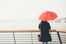 Woman Standing At The Balcony Looking At The River And Holding Umbrella