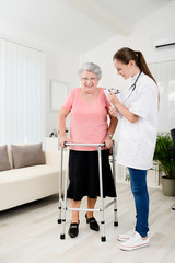 young doctor checking rehab medical progress to an elderly woman at home